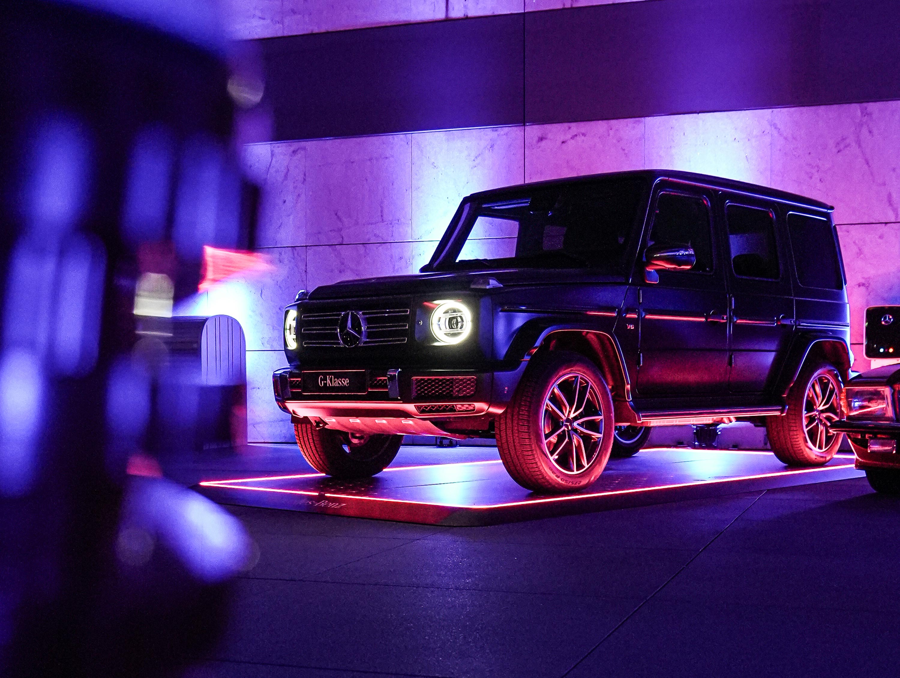 Schwarzer Geländewagen auf beleuchtetem Fahrzeugpad in einem Raum mit lila Licht.