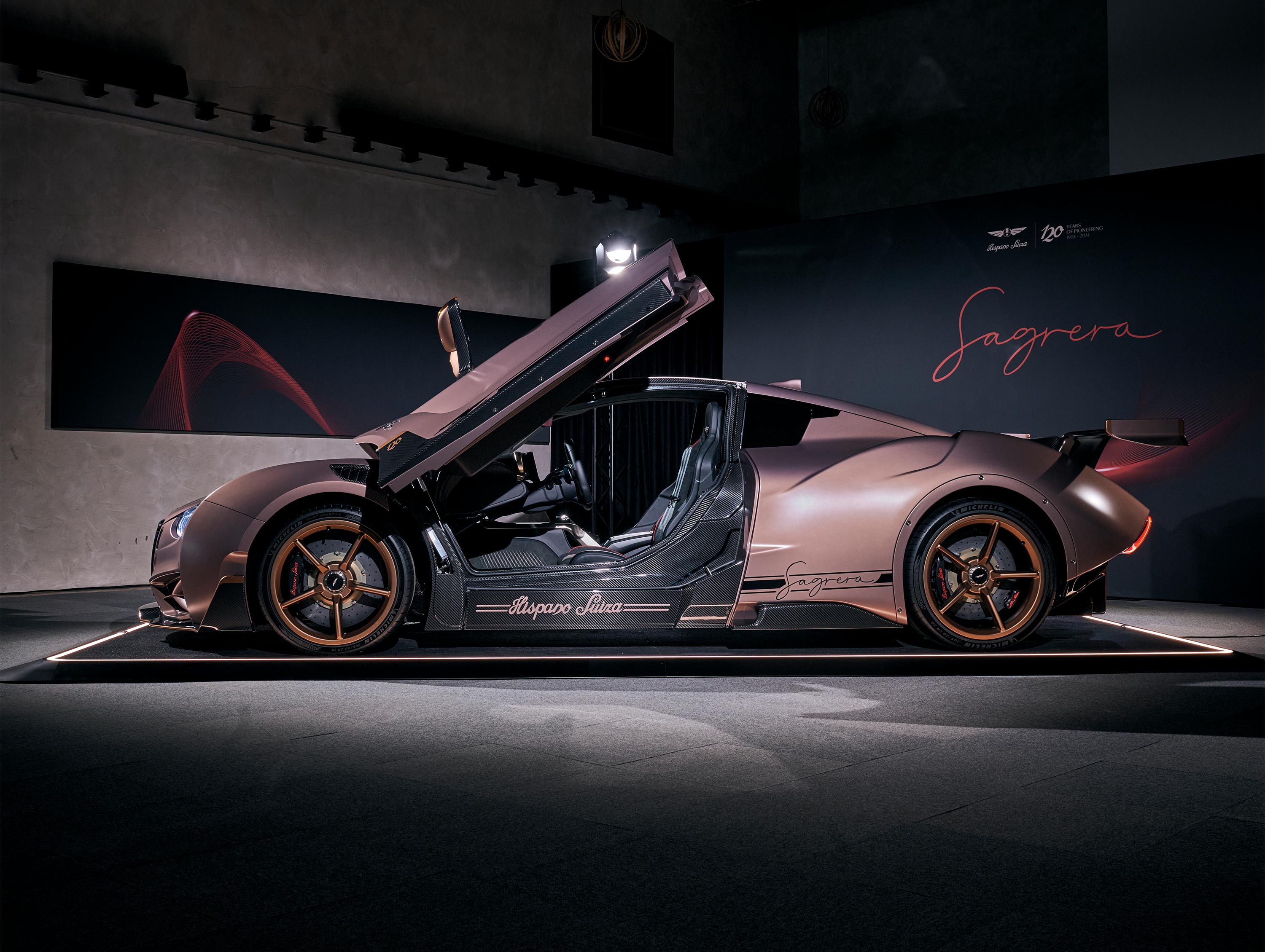 Sportwagen mit geöffneten Flügeltüren in einem Ausstellungsraum, seitlich aufgenommen, mit stilvollem Hintergrund.