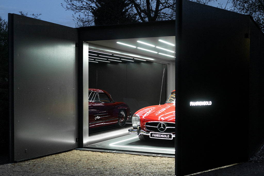 Moderne Garage mit zwei Oldtimern, beleuchtet durch LED-Streifen, offene Türen zeigen das Logo "FahrenGold".