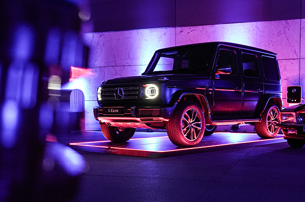 Schwarzer Geländewagen auf beleuchtetem Fahrzeugpad in lilafarbenem Licht in einer Garage.
